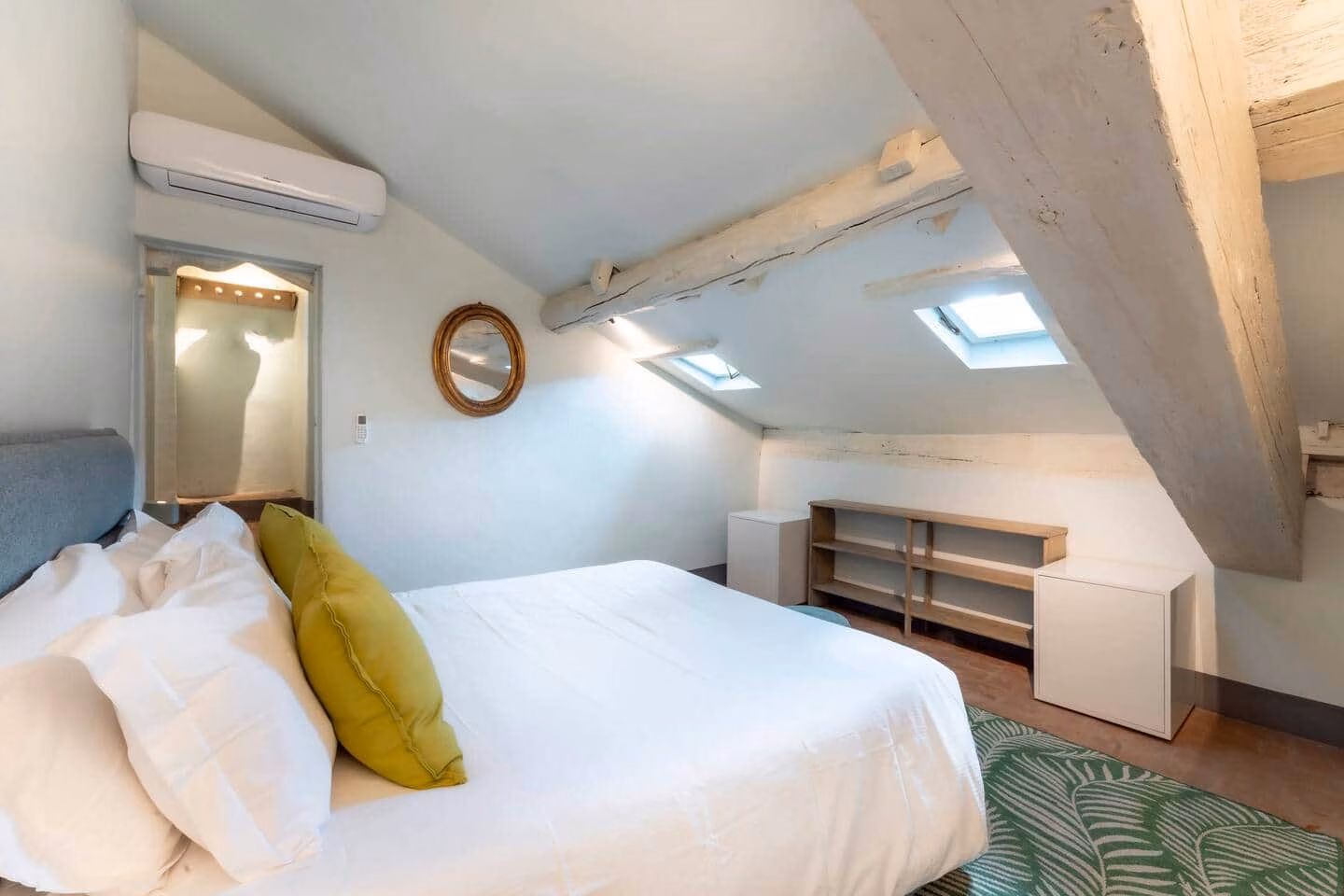 Loggia — attic bedroom with a sloped whitewashed ceiling, exposed beams, twin skylights and a double bed in white linen
